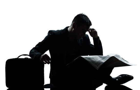 one caucasian man sitting reading newspaper despair full length silhouette in studio isolated white background