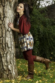Young beautiful woman with colorful autumn fashionable clothing relaxing on a urban park.