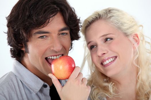 Woman looking at man eating an apple