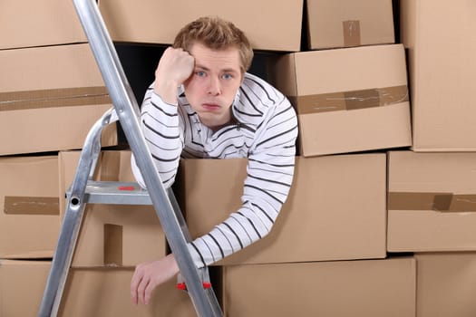 Man stuck behind stacks of cardboard boxes