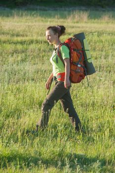 Happy smiling woman in field. Green grass in foreground and clear sky in background.