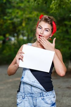 Beautiful pin-up girl in denim overalls and a red bandana holding copyspace