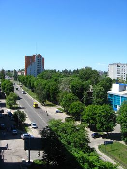 Panorama from a window on city with multystorey houses and many green trees