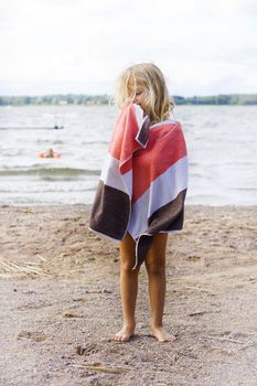 A little girl wrapped up in a towel after a swim at the beach