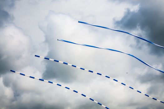 Picture of long blue white flying kites with dark clouds on sky