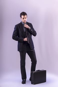 View of a young business man standing against a grey  background. 