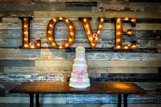 Image of a wedding cake with the word love as sinage on a rustic background