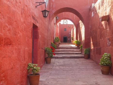 Red painted walls and arches design of alleyway through the Santa Catalina Monastery in Arequipa, Peru.