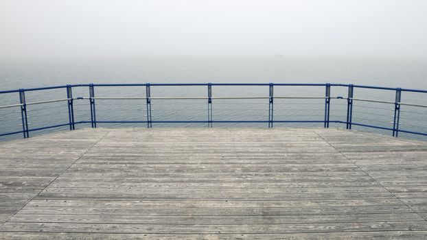 wooden deck with metallic handrails with foggy lake waters behind