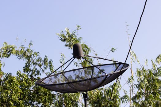 Satellite dish and cloudy blue sky background  and tree behind