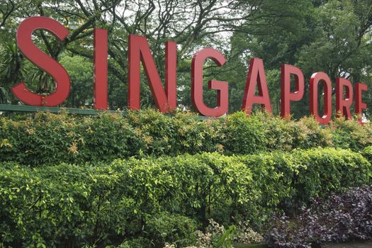 big red letters Singapore stay in green fresh bushes with park trees behind 
