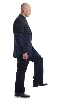 Side view of man in suit stepping up isolated on white