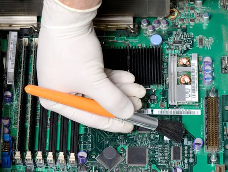 technician brushing dust of mother board