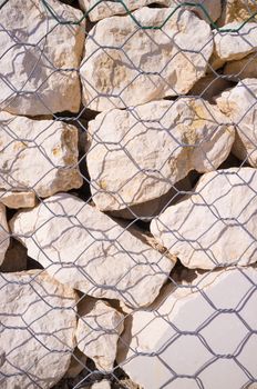 Detail take of stones behind the mesh of a gabion wall