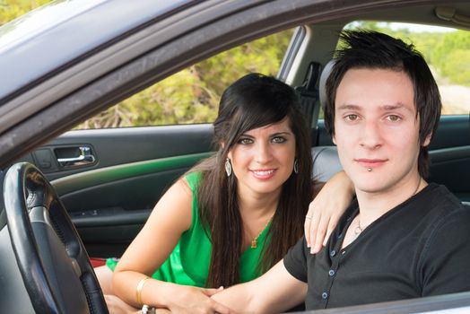 Cuple in their  twenties inside a car looking at camera