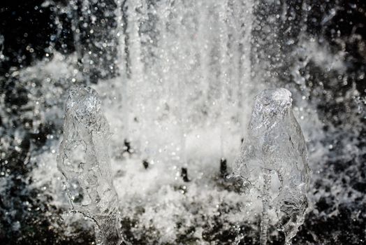 Closeup on splashes of fountain water on a sunny day