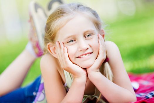 Image of little cute girl lying on grass in park