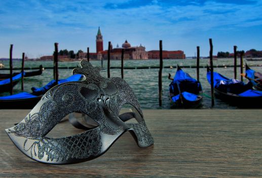 Black Venetian mask over a Venetian panorama with gondolas and San Marco