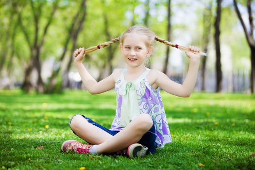 Image of little cute girl sitting on grass in park