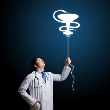 Young male doctor holding balloon with medicine sign