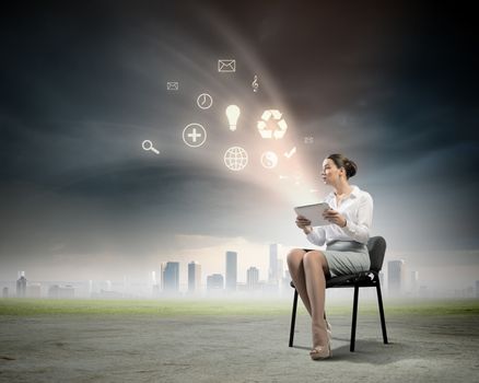 Image of businesswoman sitting on chair with tablet pc in hands