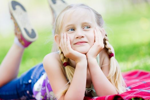 Image of little cute girl lying on grass in park