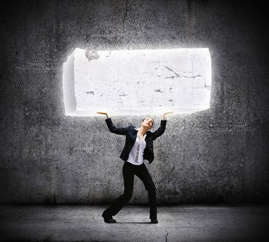 Image of young businesswoman holding burden above head