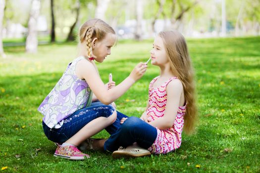 Image of two little cute girl playing on grass in park