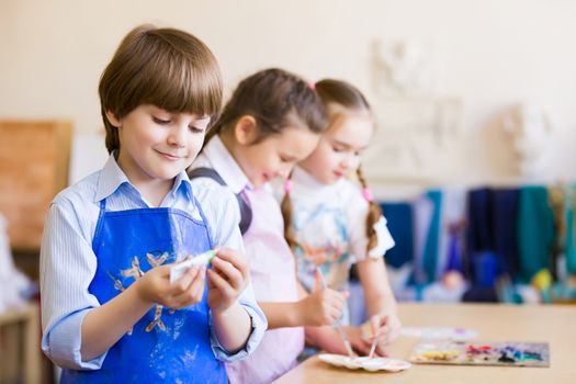 Little children painting and playing at kindergarten