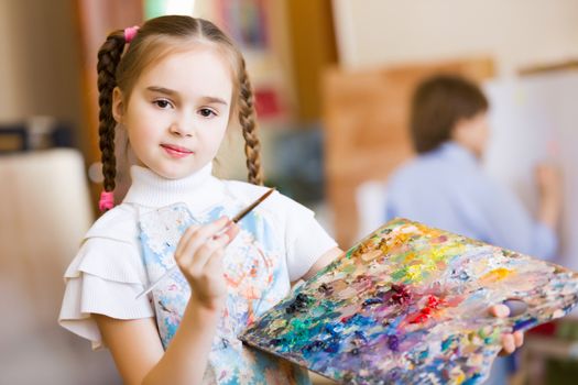 Little cute girl with paint brush and easel