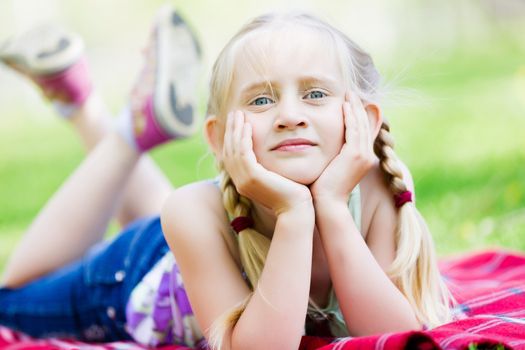 Image of little cute girl lying on grass in park