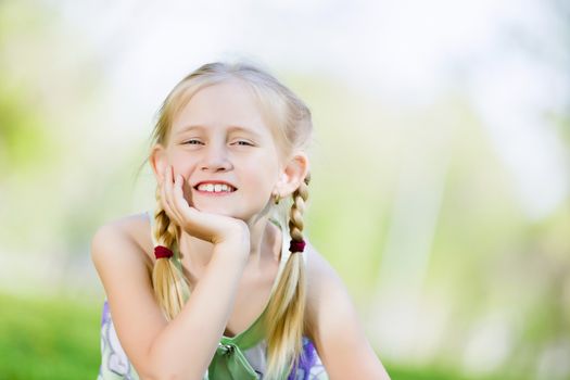 Image of little cute girl sitting on grass in park