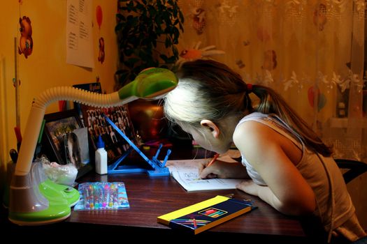 schoolgirl learns lessons at the table in her room