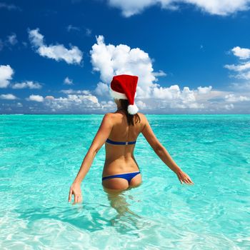 Woman in santa's hat in bikini at tropical beach
