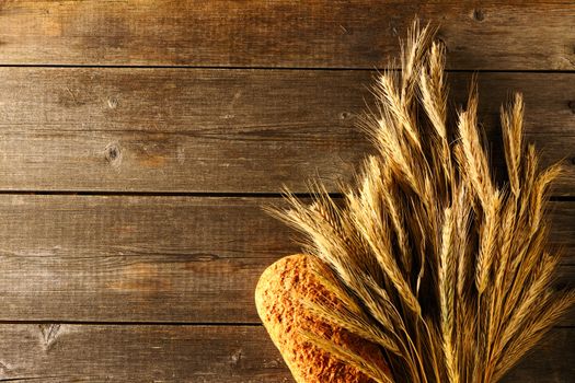 Rye spikelets and bread on wooden background