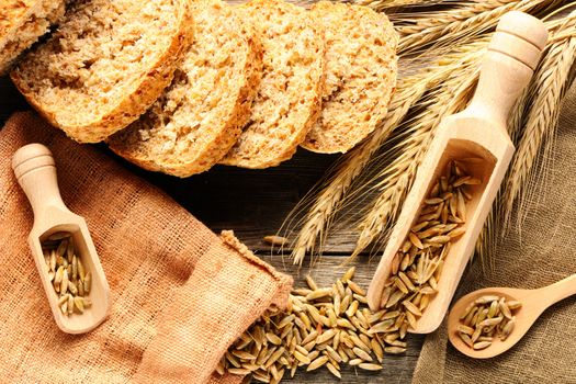 Rye spikelets and bread on wooden background