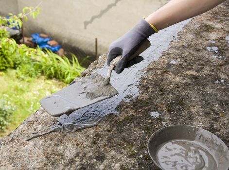 Close-up of woman's hand holding a trowel, applying mortar 