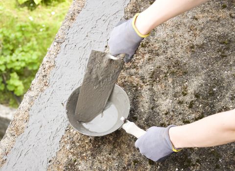 Close-up of woman's hand holding a trowel, applying mortar 