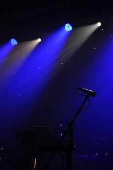Microphone on stage with blue light on the background 