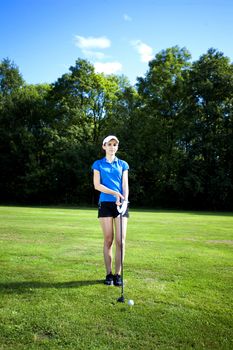 Pretty girl playing golf on grass in summer