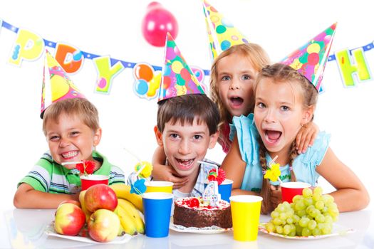 Group of adorable kids having fun at birthday party with birthday cake