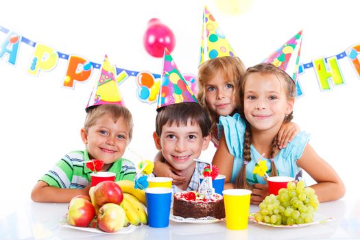 Group of adorable kids having fun at birthday party with birthday cake