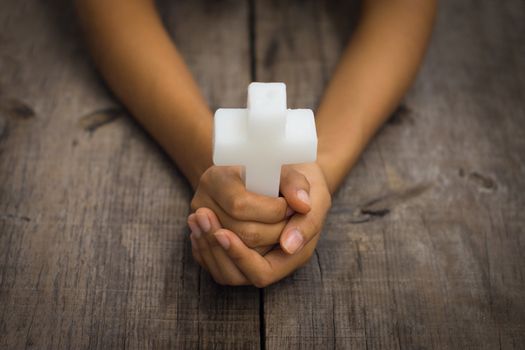 A person holding a white Religious Cross on white background