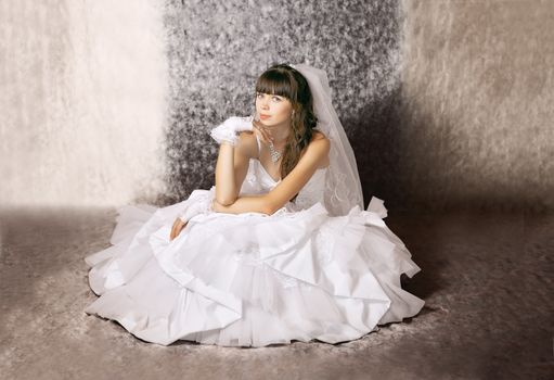 The bride with a thoughtful expression on his face in a wedding dress in a sitting position