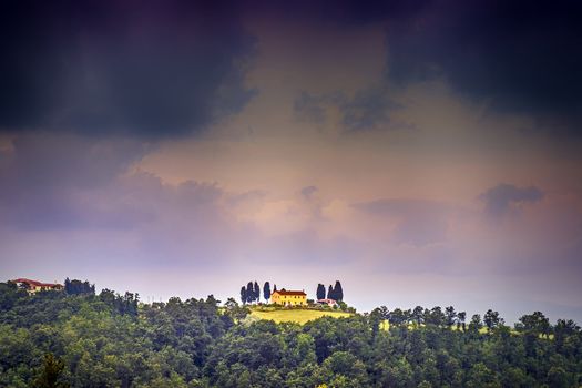 picture of a landscape with house and dark storm clouds in tuscany, italy