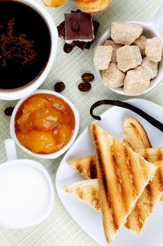 Arrangement of Coffee Cup, Milk, Toasts with Chocolate, Sugar Cubes and Apricot Jam on Checkered background. Top View