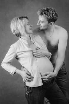 Loving happy couple, pregnant woman with her husband, black and white, looking at each other