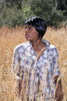 Close-up of a lovely young woman standing in tall grass.