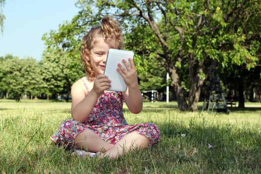 happy little girl with tablet pc in park