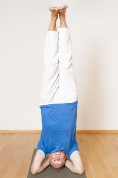 An image of a man doing yoga exercises - Salamba Shirshasana Head Stand